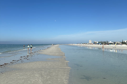 A long sandbar and beach under a clear blue sky