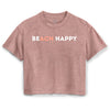 A heathered dusty rose short-sleeve crop top featuring the text 'BEACH HAPPY' printed across the chest, with 'BEACH' in white and 'HAPPY' in a coral-orange color. A small red and white logo is visible on the right sleeve.